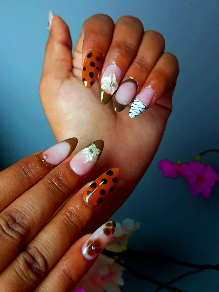 Beautiful almond-shaped nail extensions with floral and animal print designs at a nail salon in Jhamsikhel