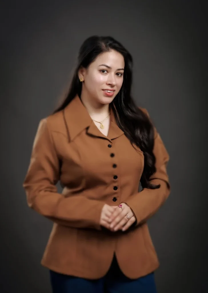 Professional portrait of a woman wearing a brown blazer against a dark studio background.